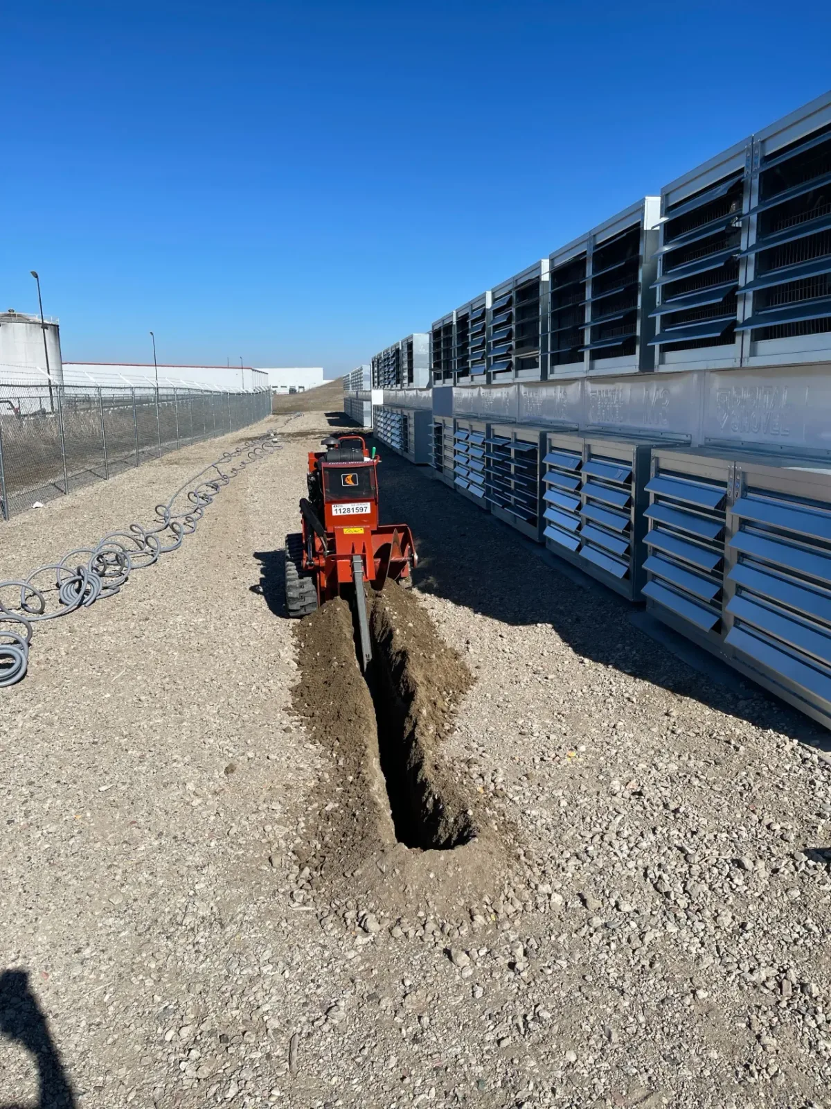 Utility trenching work next to mining containers during site construction